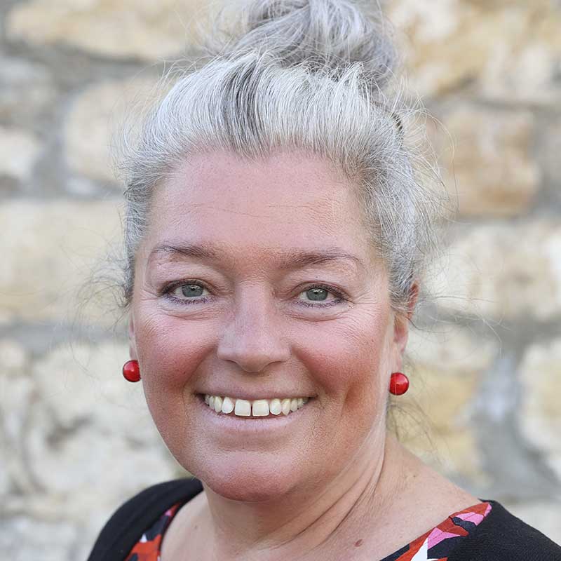 Eine Frau mit grauen Haaren und einem freundlichen Lächeln.