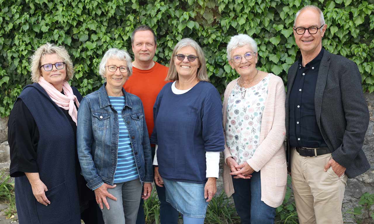 Ein Team von sechs Personen vor einer begrünten Wand