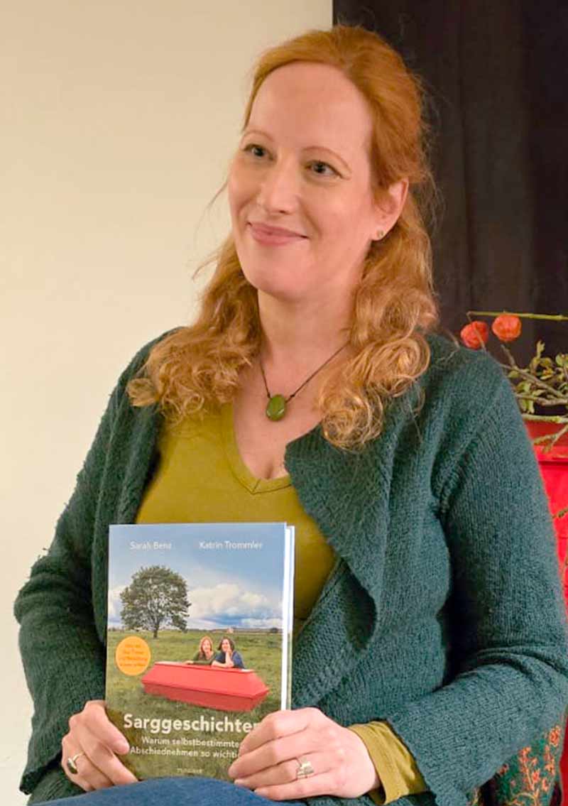 Eine Frau hält ein Buch mit einer Abbildung einer schwangeren Frau.